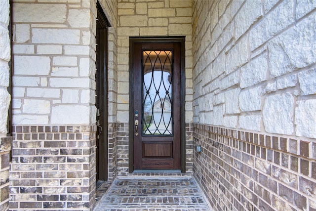 doorway to property featuring stone siding and brick siding