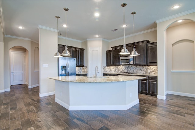 kitchen with appliances with stainless steel finishes, a sink, a center island with sink, and decorative light fixtures