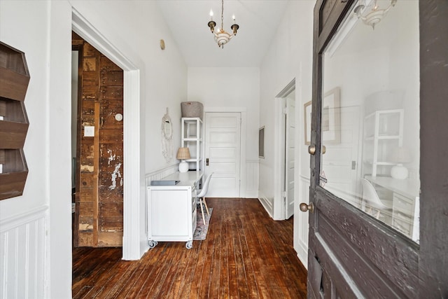 interior space with an inviting chandelier, dark wood finished floors, a wainscoted wall, and a decorative wall