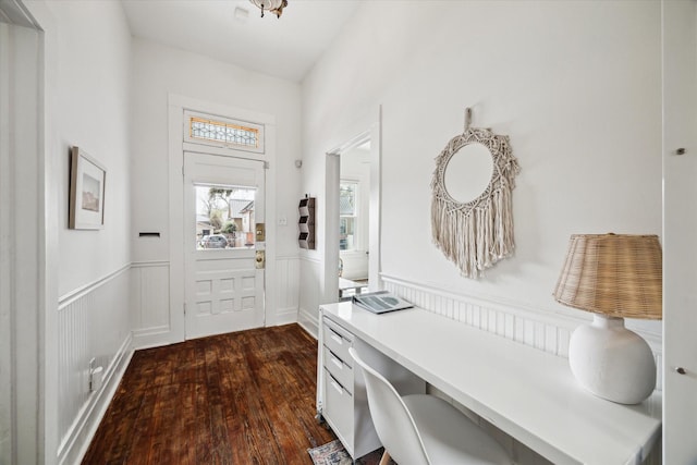 entrance foyer with dark wood-style flooring and wainscoting