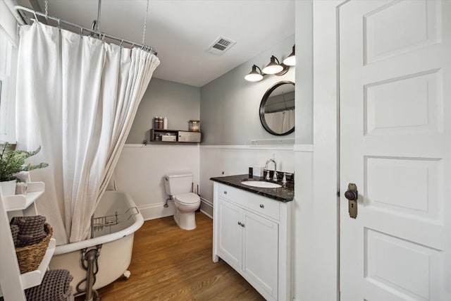 bathroom featuring visible vents, toilet, a tub, wood finished floors, and vanity