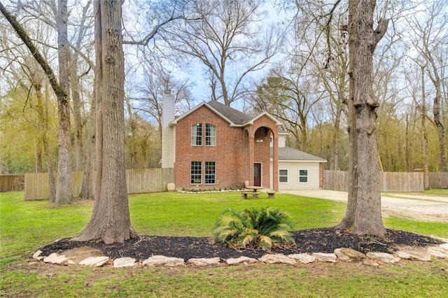 traditional-style house featuring a chimney, fence, a front lawn, and brick siding