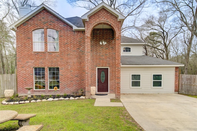 traditional home featuring brick siding, a chimney, fence, driveway, and a front lawn