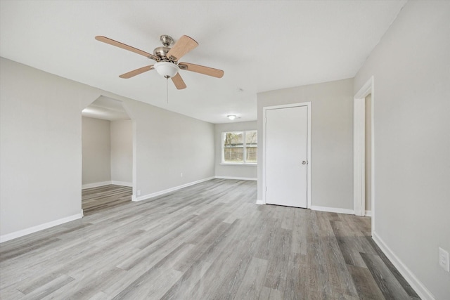 empty room featuring light wood-type flooring, a ceiling fan, and baseboards