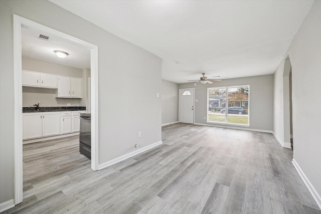 unfurnished living room with visible vents, ceiling fan, light wood-style flooring, and baseboards