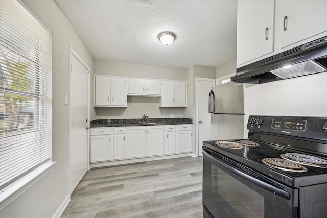 kitchen with dark countertops, electric range, freestanding refrigerator, white cabinets, and under cabinet range hood