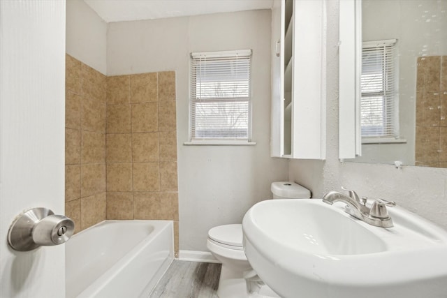 full bathroom with shower / bathing tub combination, toilet, a sink, wood finished floors, and baseboards