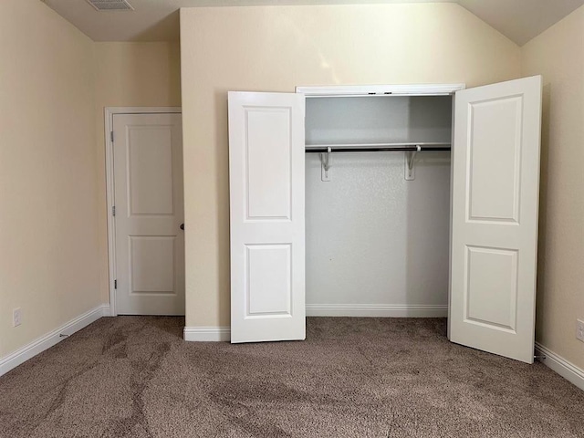 unfurnished bedroom with a closet, baseboards, carpet, and vaulted ceiling