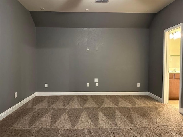 carpeted spare room featuring lofted ceiling, visible vents, baseboards, and a sink