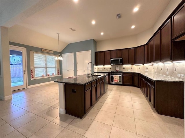 kitchen featuring a sink, stainless steel appliances, visible vents, and dark stone counters