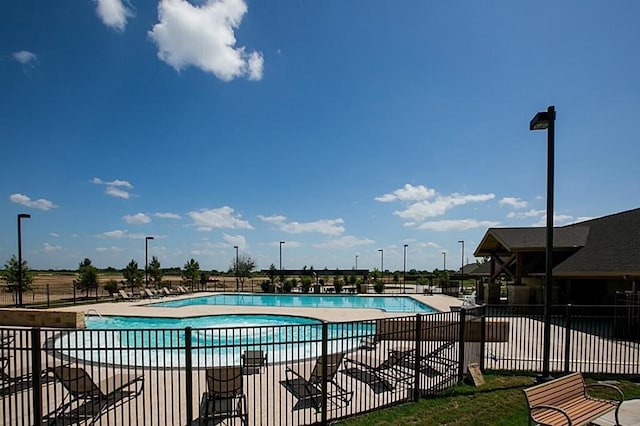 community pool with a patio area and fence