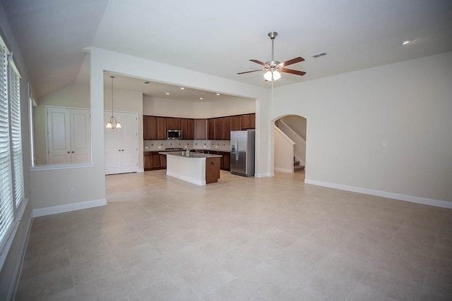 kitchen featuring an island with sink, tasteful backsplash, open floor plan, appliances with stainless steel finishes, and ceiling fan