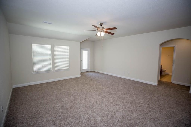 carpeted empty room featuring visible vents, arched walkways, baseboards, and ceiling fan