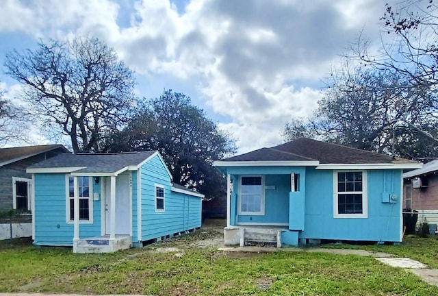 back of property featuring entry steps, a shingled roof, and a lawn