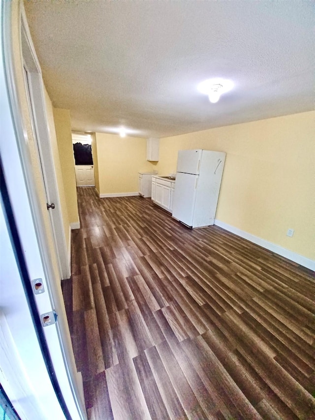 interior space featuring dark wood-style floors, a textured ceiling, and baseboards