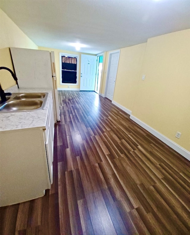 kitchen with dark wood-style flooring, a sink, baseboards, open floor plan, and light countertops