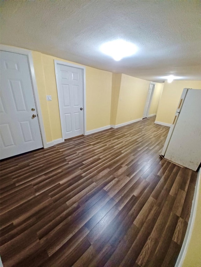 finished basement featuring a textured ceiling, dark wood finished floors, and baseboards