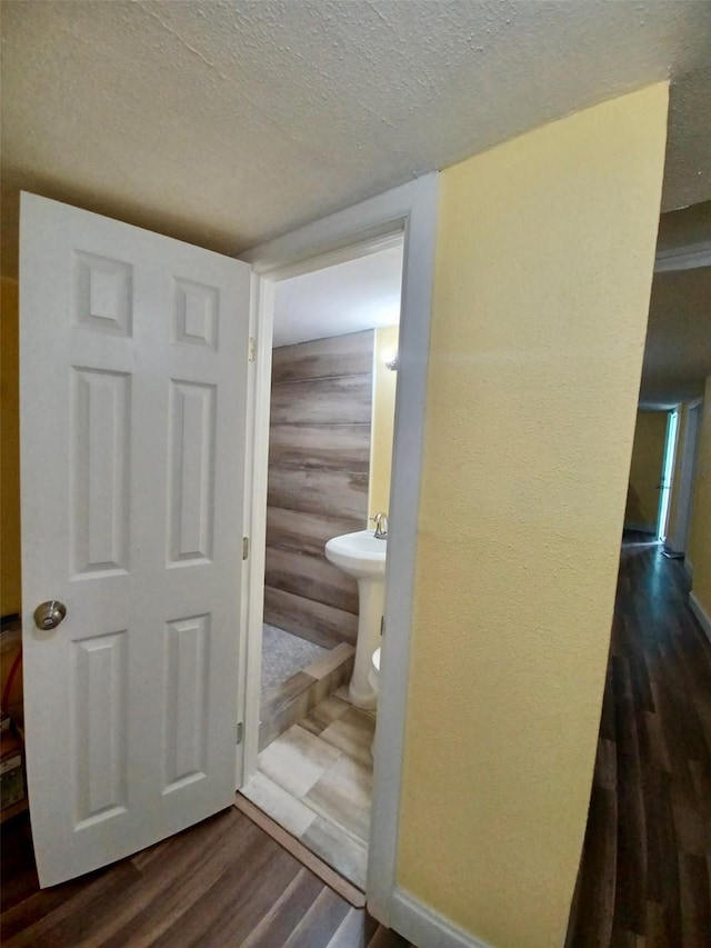 bathroom featuring a textured ceiling, wood finished floors, and baseboards