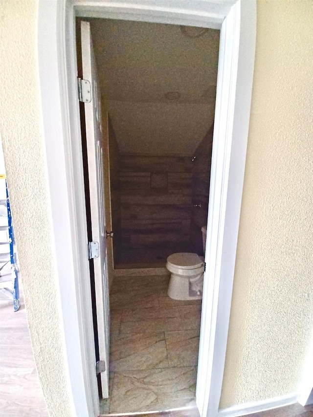 bathroom featuring a textured wall and toilet