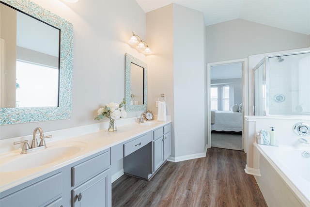 ensuite bathroom featuring lofted ceiling, a stall shower, a sink, and wood finished floors