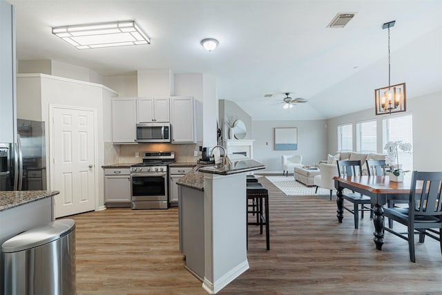 kitchen with a breakfast bar area, a peninsula, visible vents, open floor plan, and appliances with stainless steel finishes