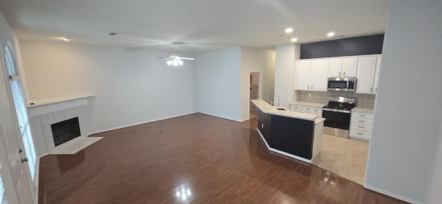 kitchen featuring white cabinets, open floor plan, a kitchen island with sink, stainless steel appliances, and light countertops