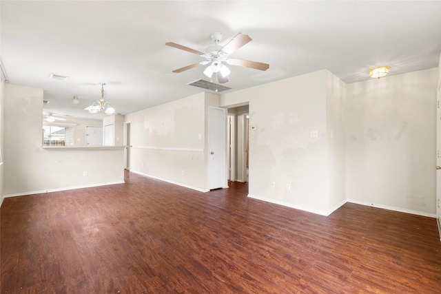 empty room with dark wood-style floors, baseboards, and ceiling fan with notable chandelier