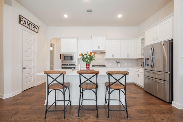 kitchen featuring light countertops, visible vents, appliances with stainless steel finishes, white cabinets, and a kitchen island with sink