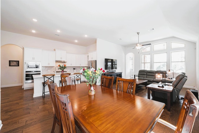 dining room featuring arched walkways, dark wood-style floors, ceiling fan, vaulted ceiling, and recessed lighting