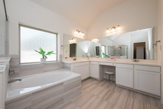 full bathroom featuring lofted ceiling, a garden tub, double vanity, and a sink