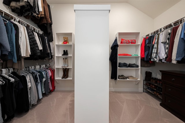 walk in closet with lofted ceiling and light colored carpet