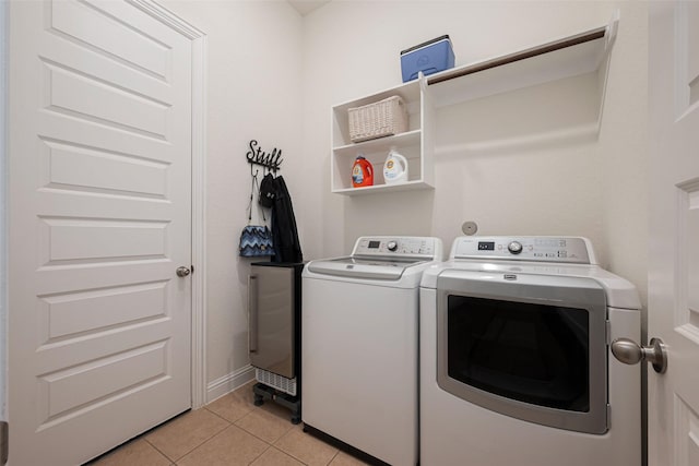 clothes washing area with light tile patterned floors, laundry area, baseboards, and washer and dryer