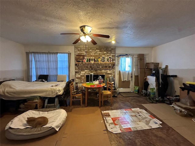 bedroom featuring a fireplace, a ceiling fan, and a textured ceiling