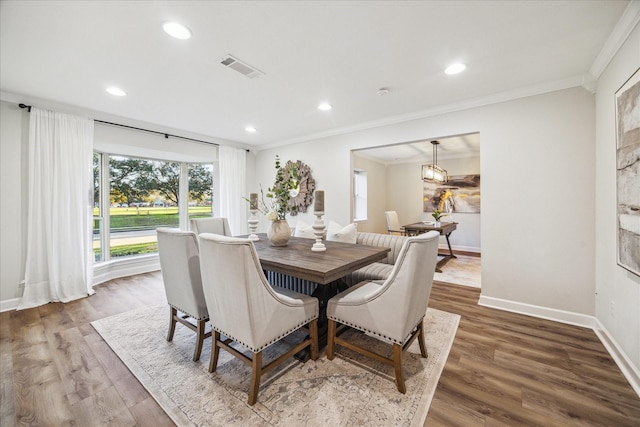 dining area with visible vents, baseboards, crown molding, and wood finished floors