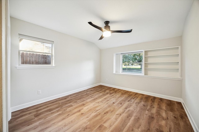 unfurnished room featuring lofted ceiling, baseboards, and wood finished floors