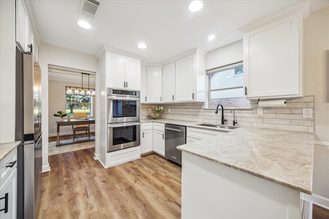 kitchen with appliances with stainless steel finishes, light wood-style floors, white cabinetry, and a sink