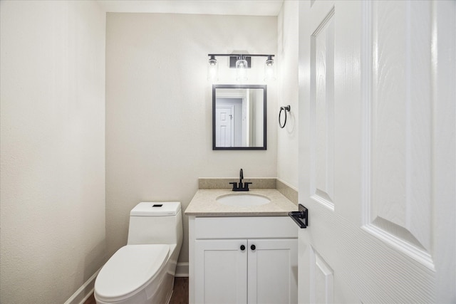 bathroom with vanity, toilet, and baseboards