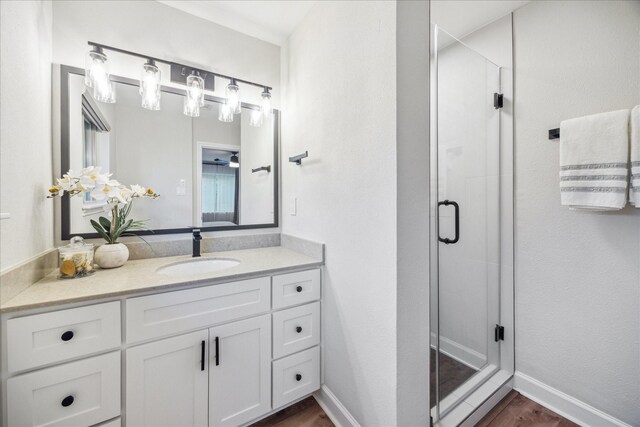 full bathroom with a shower stall, baseboards, wood finished floors, and vanity