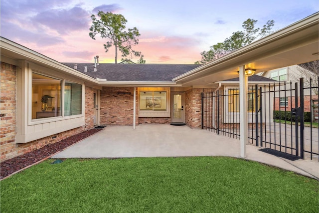 exterior space featuring brick siding, fence, roof with shingles, a lawn, and a patio area