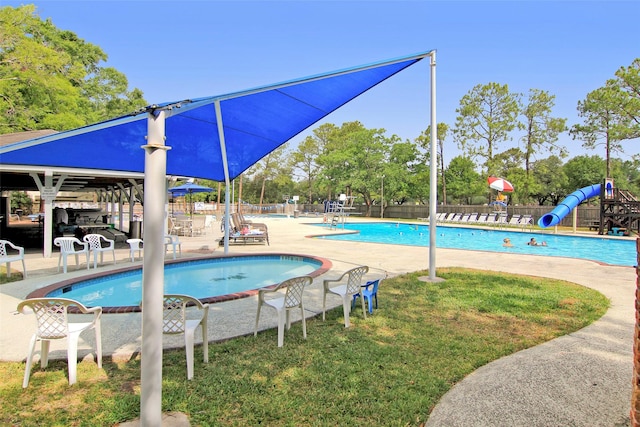 pool with a patio, a water slide, playground community, and fence