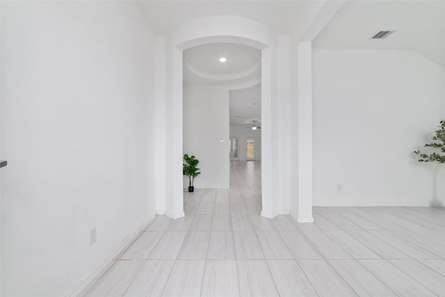 corridor with arched walkways, visible vents, and baseboards