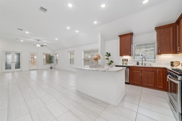 kitchen featuring light tile patterned floors, a kitchen island, open floor plan, vaulted ceiling, and appliances with stainless steel finishes