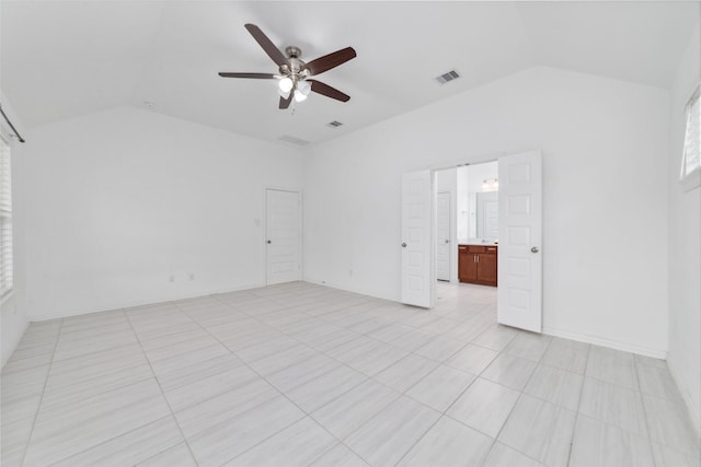 spare room with ceiling fan, light tile patterned floors, visible vents, baseboards, and vaulted ceiling