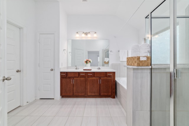 full bath with a tub to relax in, double vanity, a closet, vaulted ceiling, and a sink