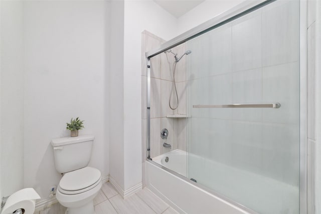 bathroom featuring enclosed tub / shower combo, tile patterned flooring, toilet, and baseboards