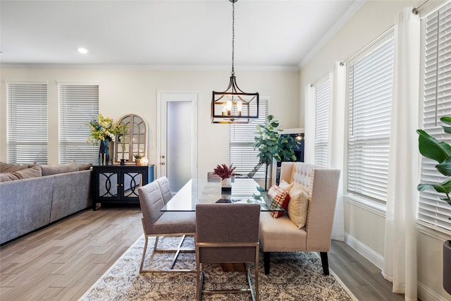 dining space with a notable chandelier, crown molding, baseboards, and wood finished floors