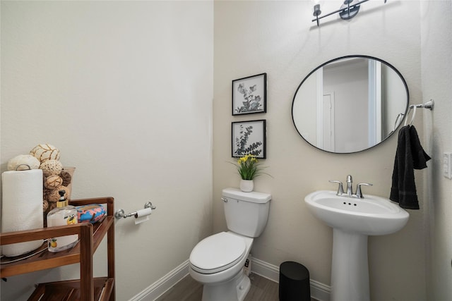 half bath featuring toilet, baseboards, and wood finished floors