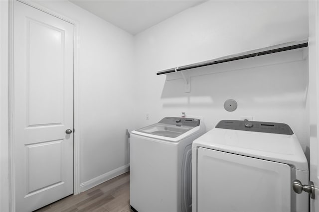 clothes washing area featuring light wood-type flooring, laundry area, independent washer and dryer, and baseboards