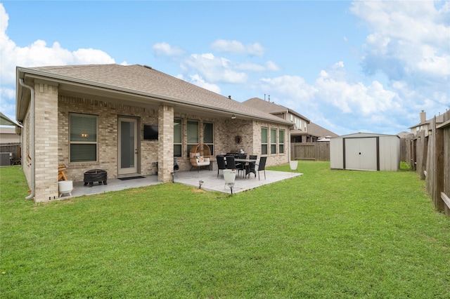 rear view of property featuring an outdoor fire pit, a patio, an outdoor structure, a shed, and brick siding