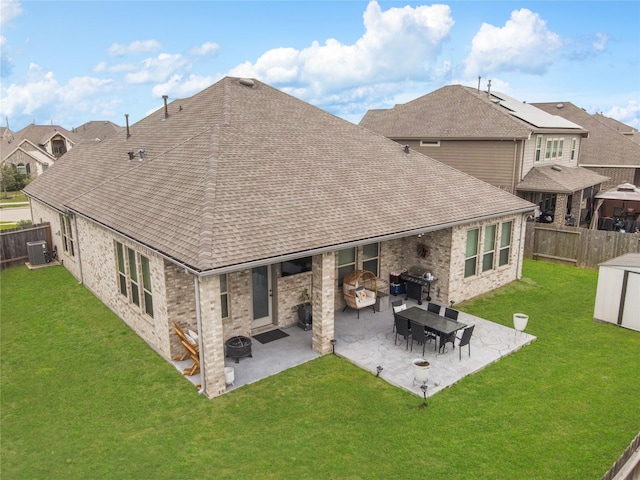 rear view of property with a yard, a fenced backyard, roof with shingles, and a patio